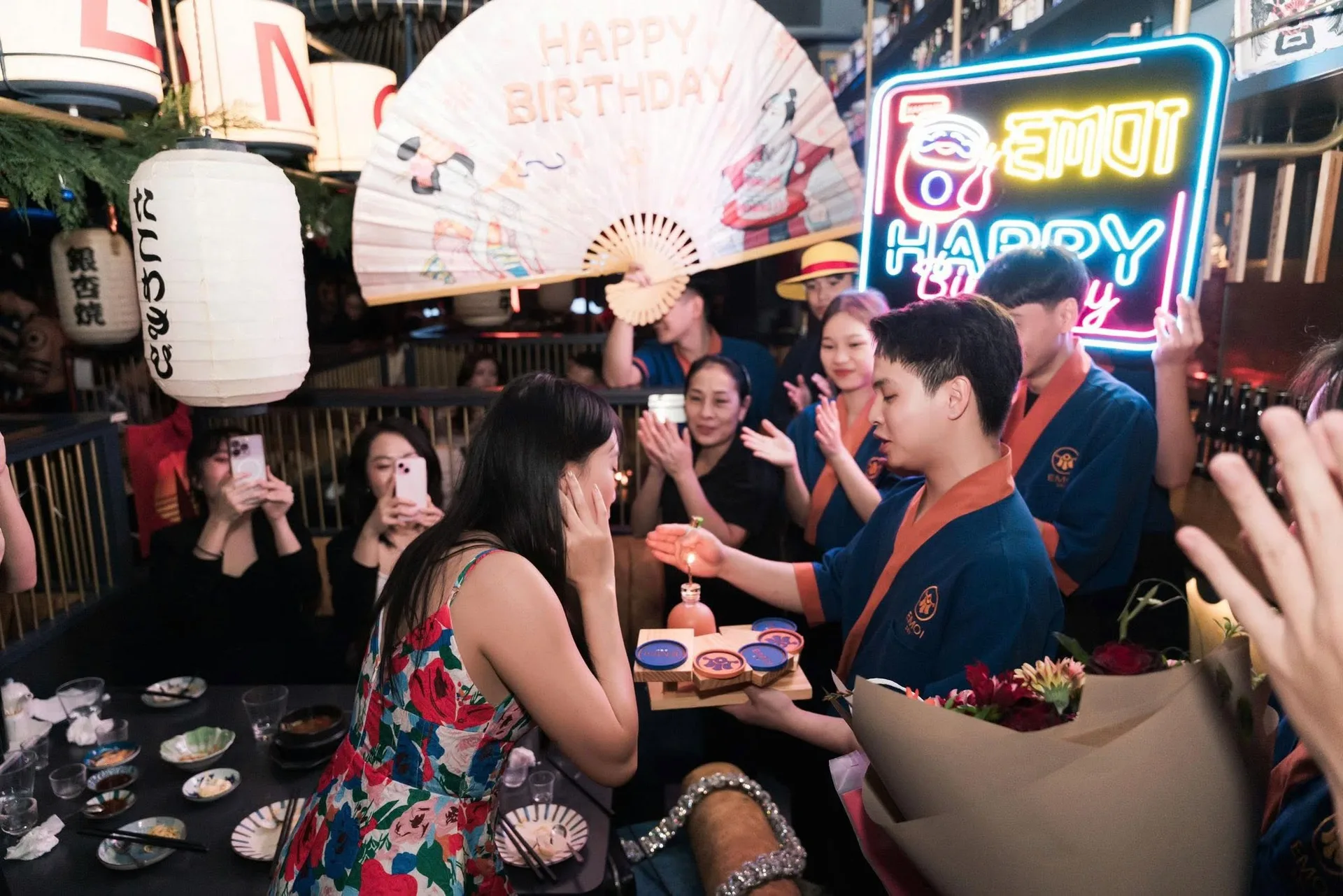 Nhân viên áo happi mở quạt giấy Happy Birthday và bảng đèn chúc mừng tại EMOI